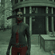 A young woman in cool black glasses and a leather jacket stands alone in a green-tinted city.